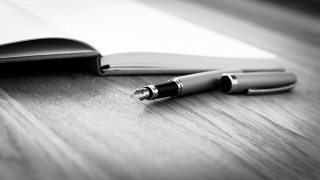 Füller und offenes Notizbuch auf Holztisch